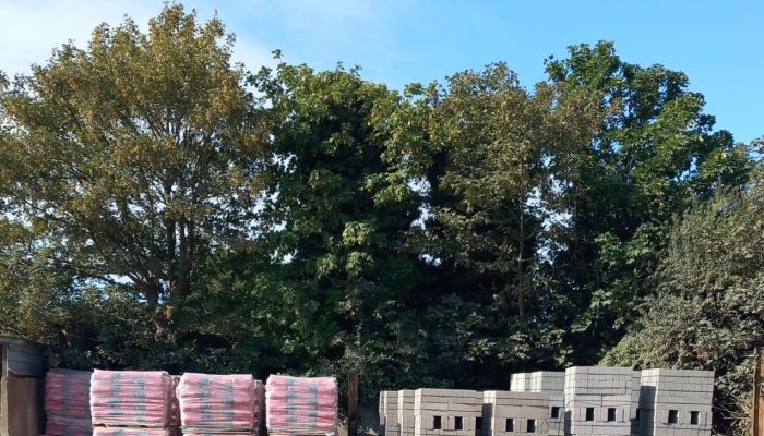 cement bags and concrete blocks piled up in a yard